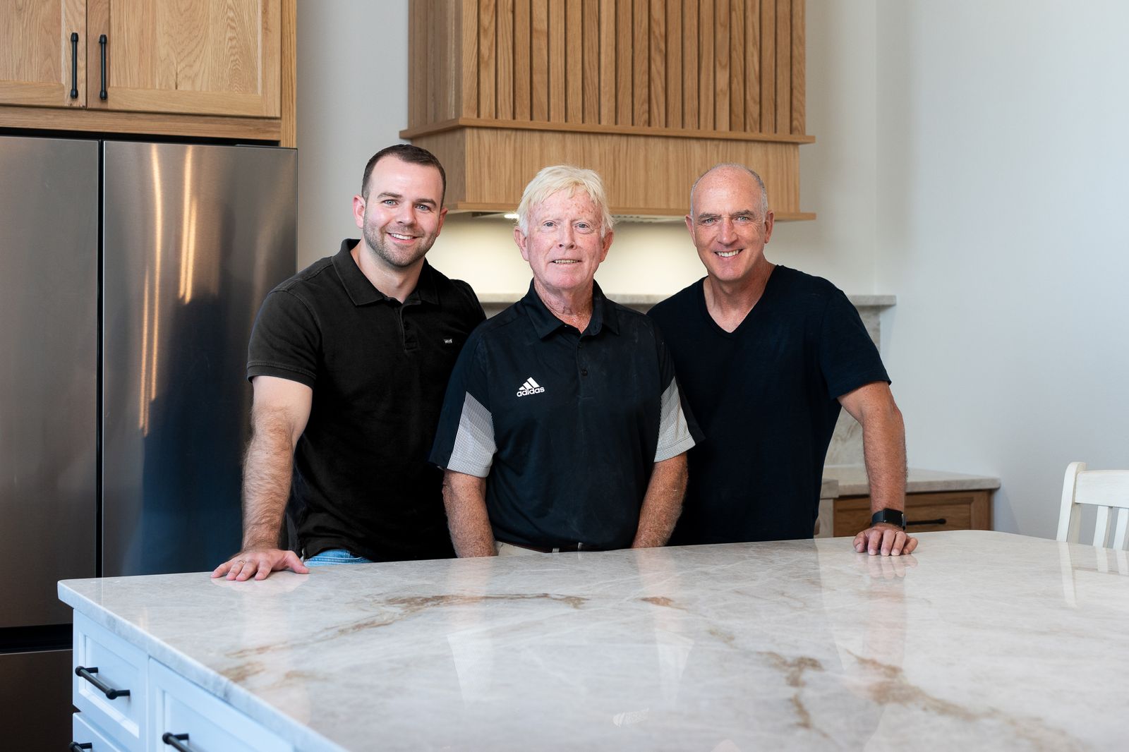 Quartz Impressions owners Aaron Bush, Pat Malloy and David Bush standing behind a finished quartz island